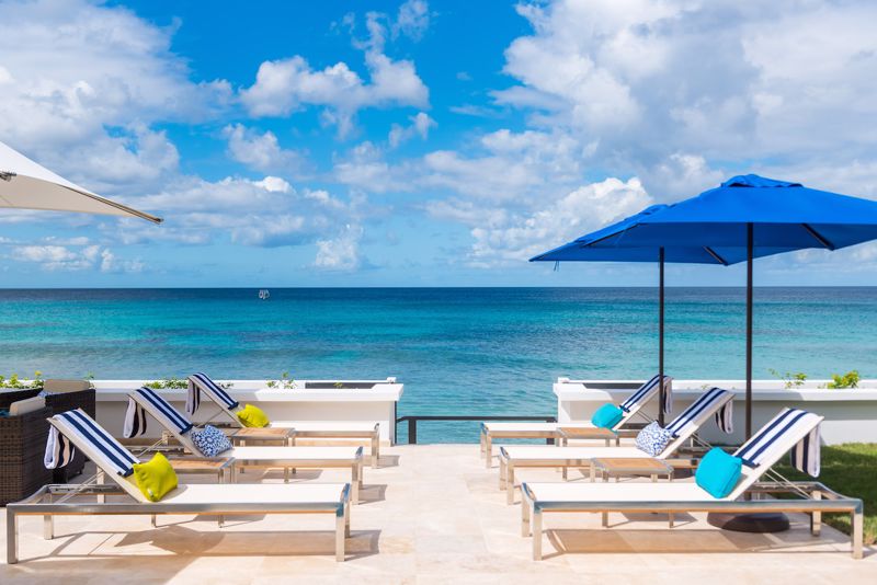 View of sunloungers and the Caribbean sea and sky at beachfront Barbados villa, Nirvana.