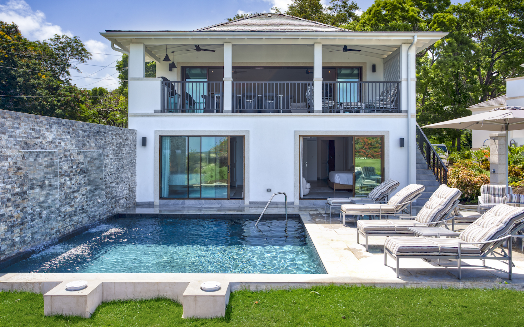 Pool and villa exterior with comfy sun loungers at Sea Bridge, Royal Westmoreland golf resort Barbados.